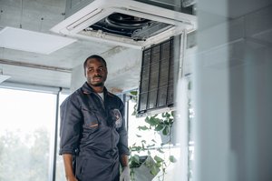 HVAC technician reviewing a HVAC system design and pricing with a homeowner in front of an HVAC unit